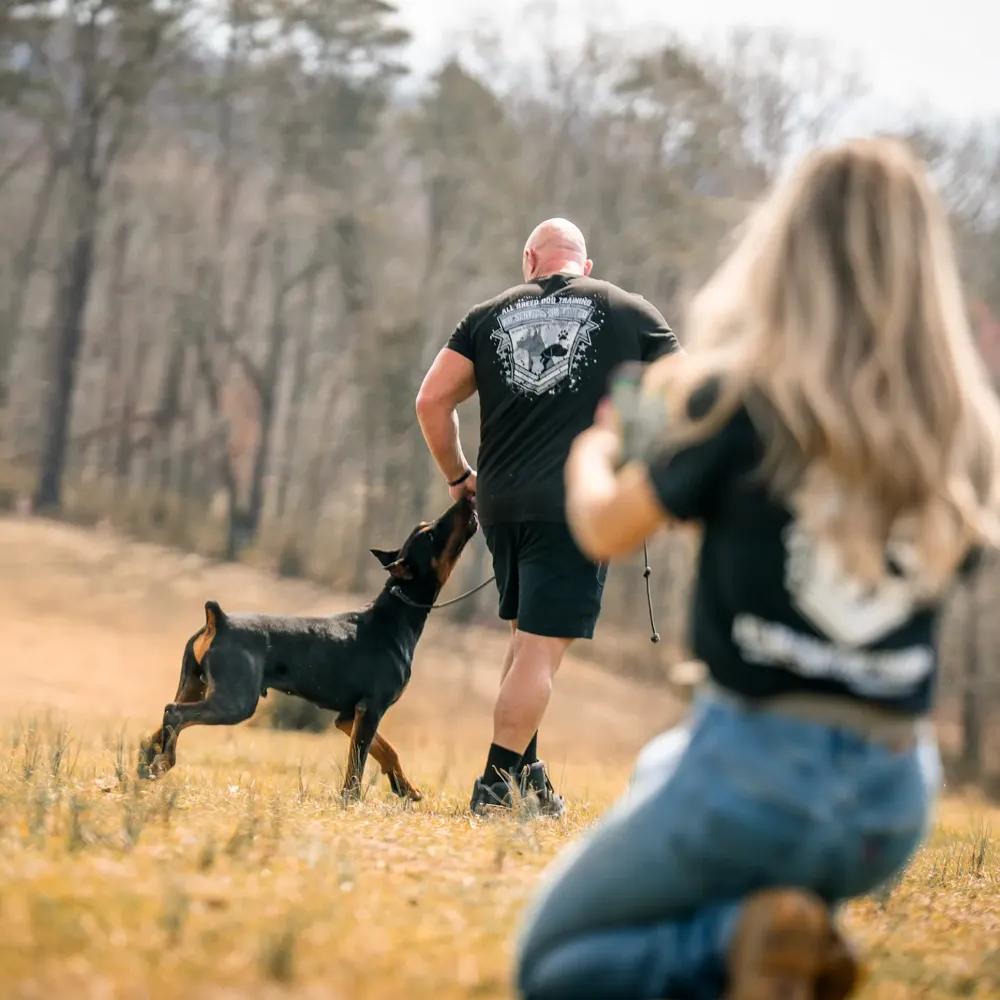 Two trainers working a Doberman on a field in the Knoxville area
