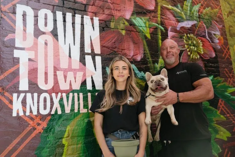 Trainers with a French bulldog in front of a downtown Knoxville mural